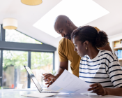 Couple checking information on paper and laptop